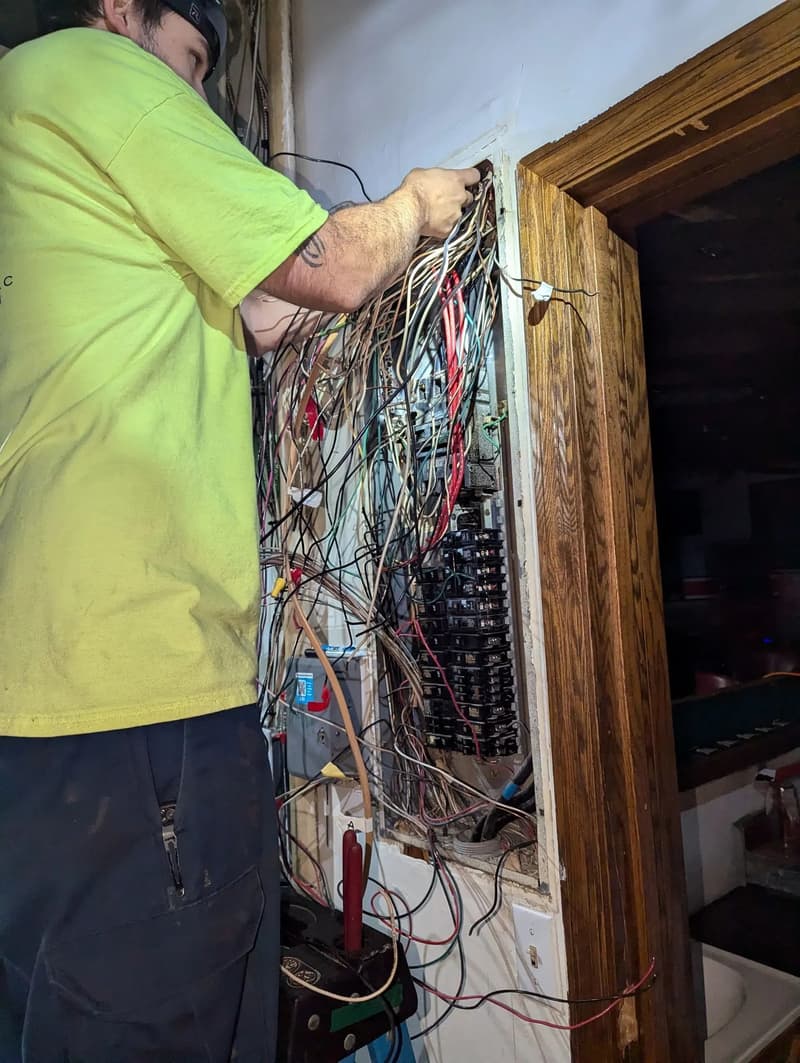 Electrician sorting wires in a crowded panel