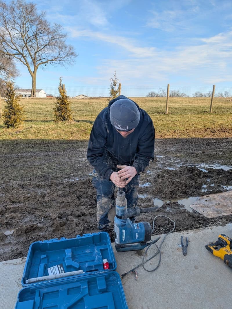 Worker using rotary hammer drill outdoors