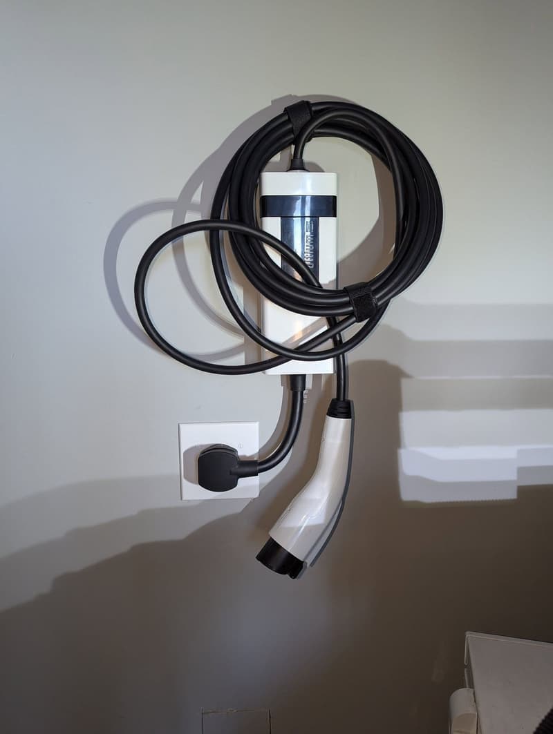 Portable EV charger hung on wall by outlet